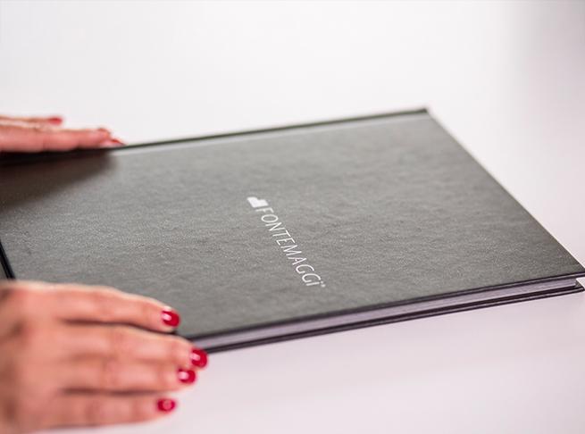 Black folder with Fontemaggi logo, hands with red nail polish.